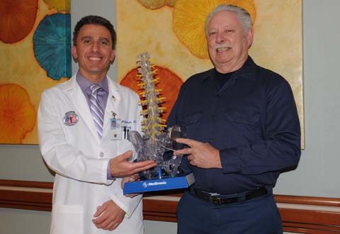 Dr. Ali Mchaourab and patient James Bridges hold a medical model of the spinal column